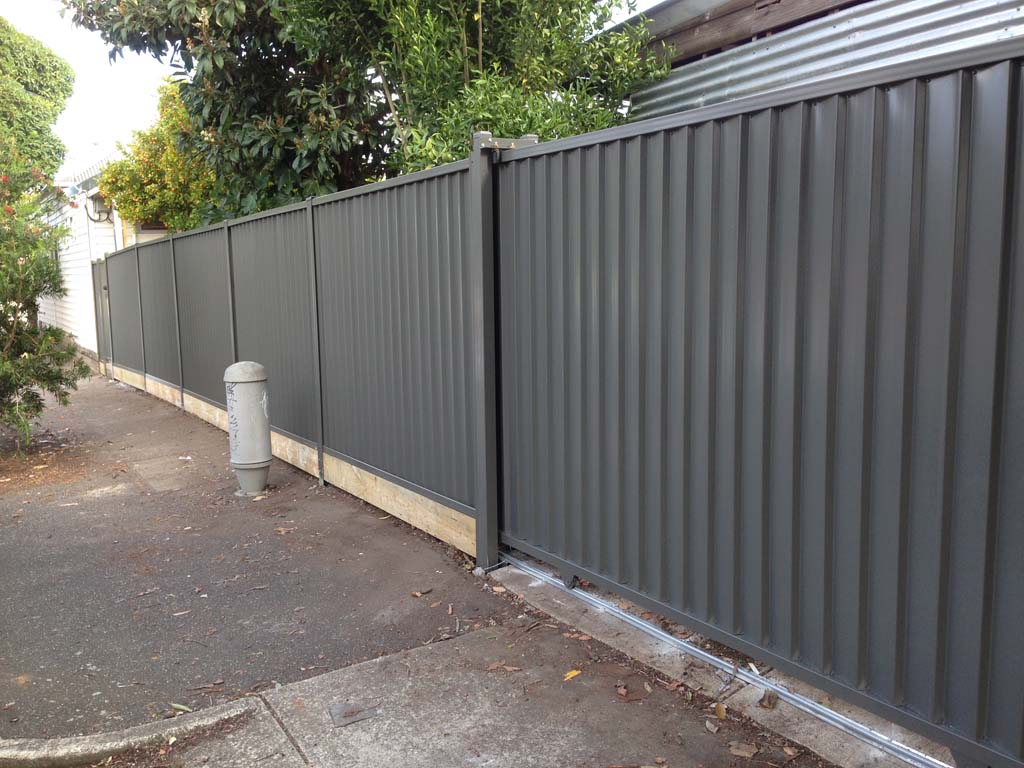 Plain colorbond with pine sleepers and a sliding gate